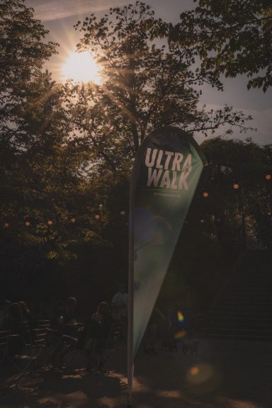 Ein Wegweiser mit der Aufschrift "Ultra Walk" vor einem Baum im Sonnenlicht.